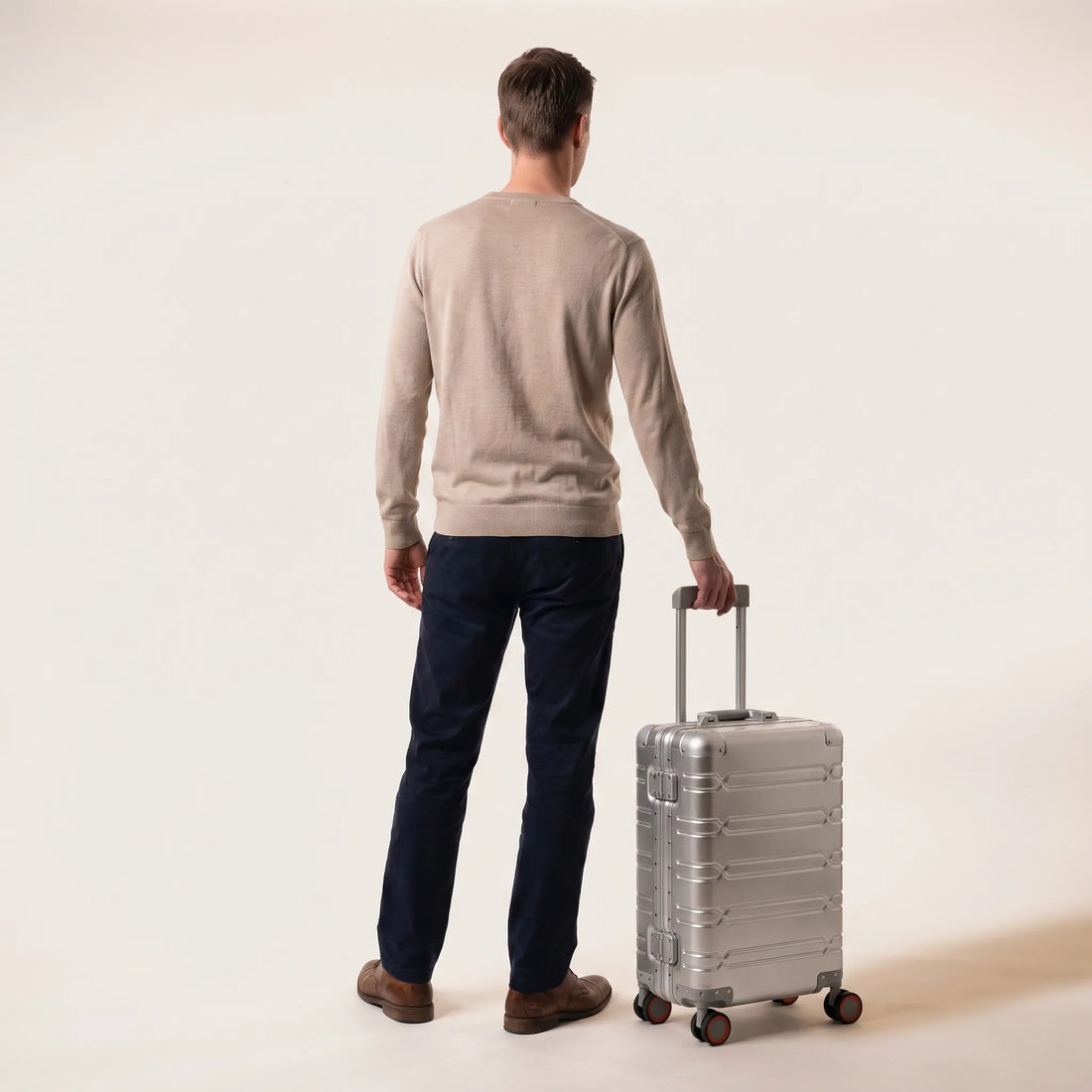 Man met de zilveren DS ONE aluminium handbagage koffer aan de trolleystang, toont het formaat