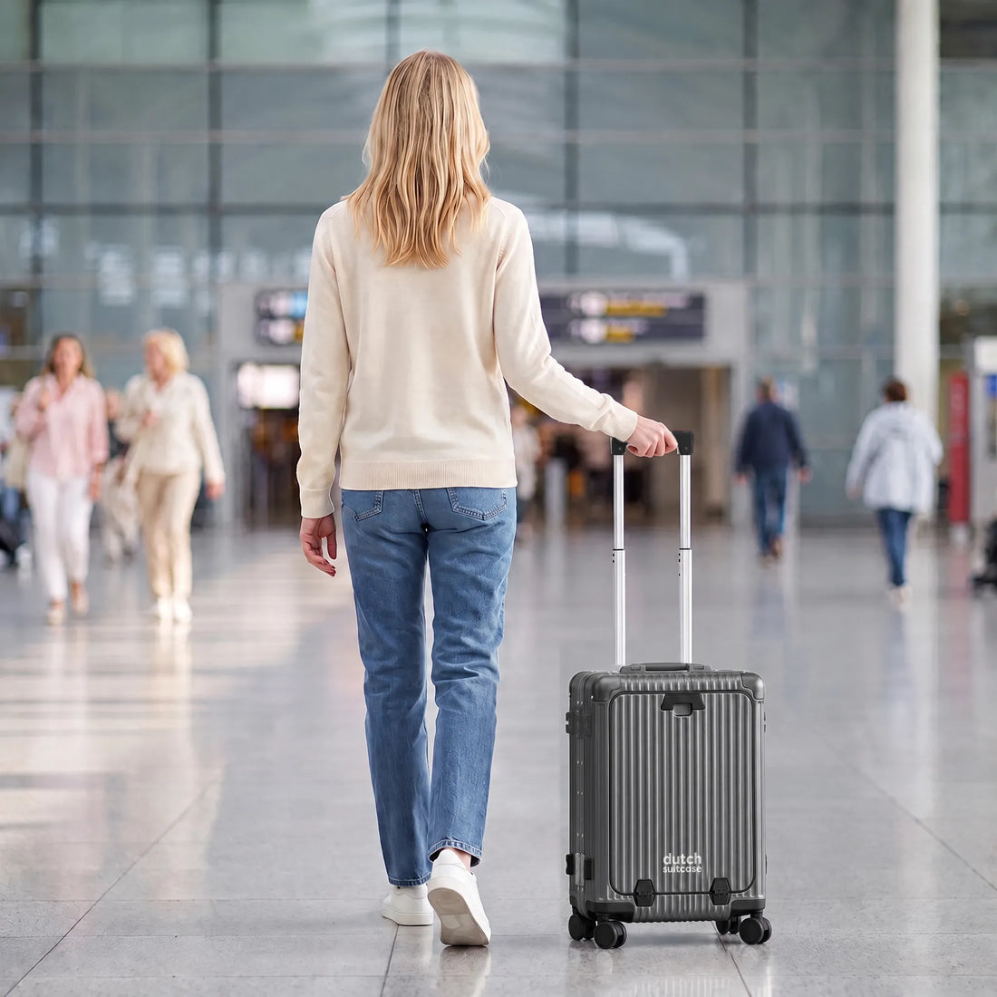 Vrouw loopt met de donkergrijze DS Front handbagage koffer aan de trolleystang door de luchthaven