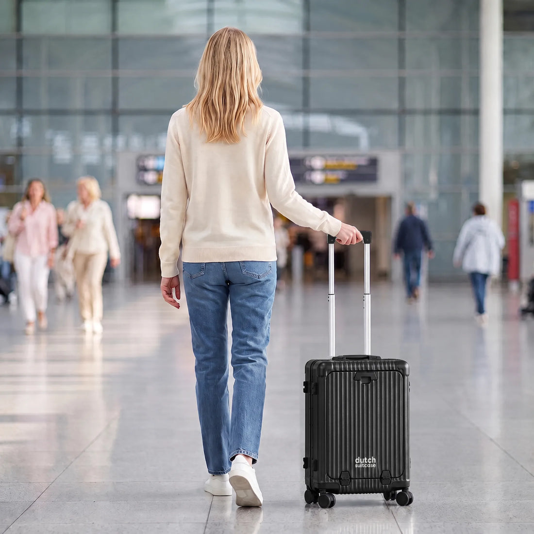 Vrouw loopt met de zwarte DS Front handbagage koffer aan de trolleystang door een luchthaventerminal