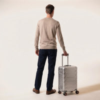 Man met de zilveren DS ONE aluminium handbagage koffer aan de trolleystang, toont het formaat