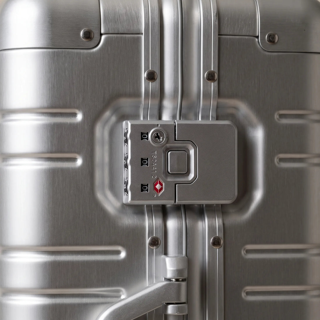 Close-up van het TSA cijferslot op de geborstelde aluminium zijkant van de DS ONE koffer