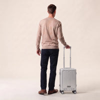 Man met de zilveren DS Front handbagage koffer aan de trolleystang, laat het handbagageformaat zien
