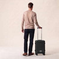 Man met de zwarte DS Front handbagage koffer aan de trolleystang, laat het handbagageformaat zien