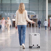 Vrouw loopt met de zilveren DS Front handbagage koffer door een luchthaventerminal