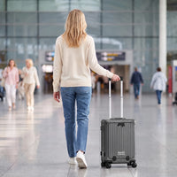Vrouw loopt met de donkergrijze DS Front handbagage koffer aan de trolleystang door de luchthaven