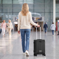 Vrouw loopt met de zwarte DS Front handbagage koffer aan de trolleystang door een luchthaventerminal