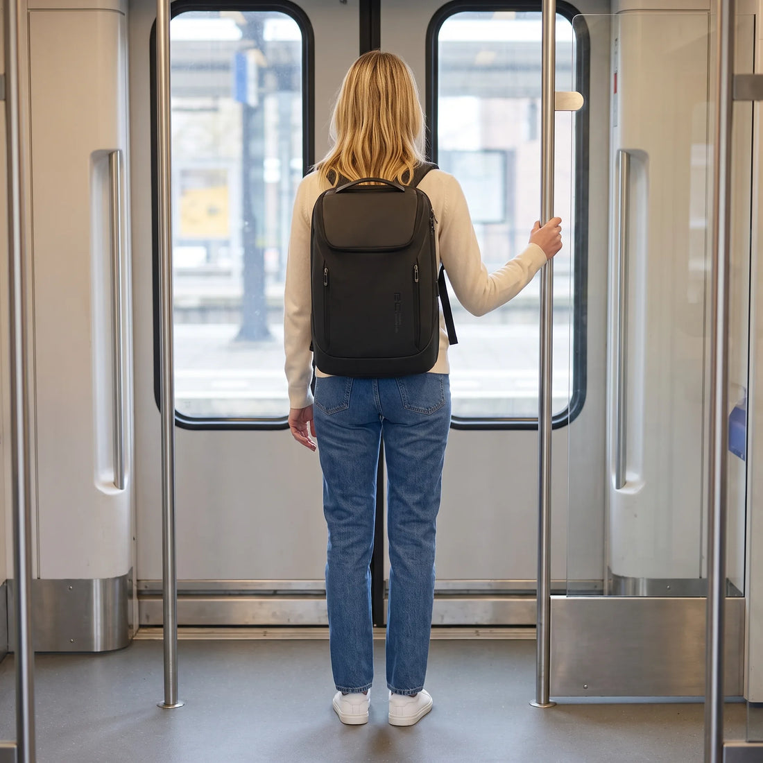 Vrouw draagt de zwarte DS Pack laptop rugzak in de trein, onderweg naar werk