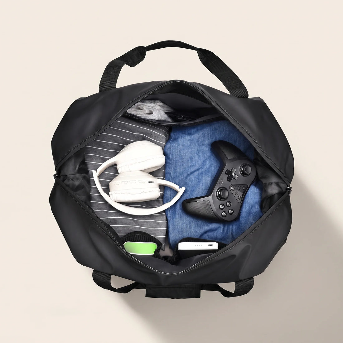 Geopende DS Dark reistas gevuld met kleding, koptelefoon en powerbank toont het ruime hoofdvak