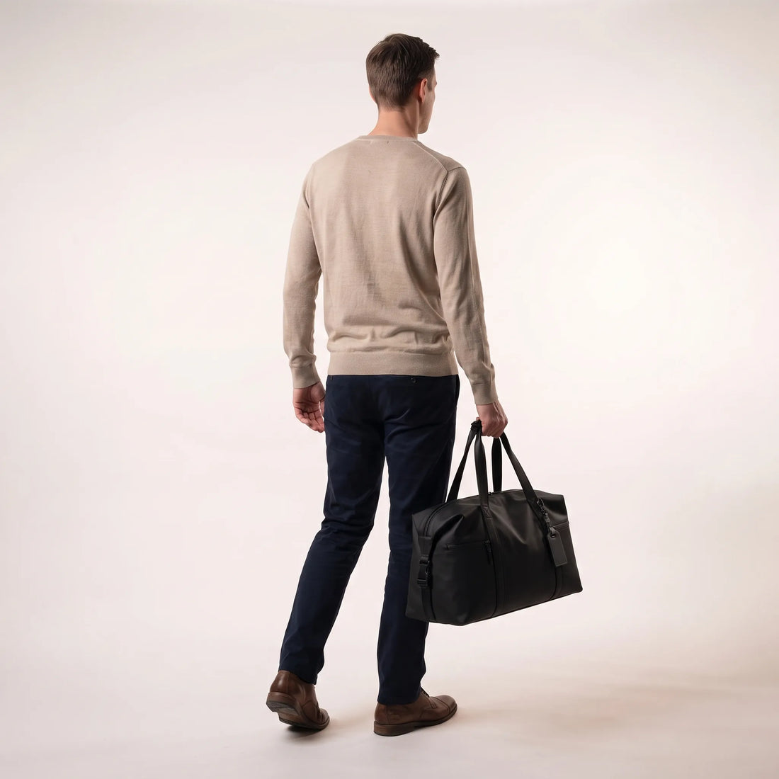 Man draagt de zwarte DS Dark weekendtas aan de handgrepen, toont het handbagage formaat