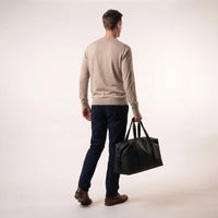 Man draagt de zwarte DS Dark weekendtas aan de handgrepen, toont het handbagage formaat